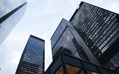 Glass and steel highrises with a grey sky, from the perspective of looking from below.