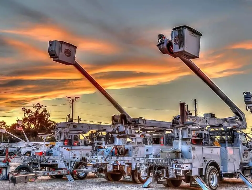 Bucket trucks under an orange sunset