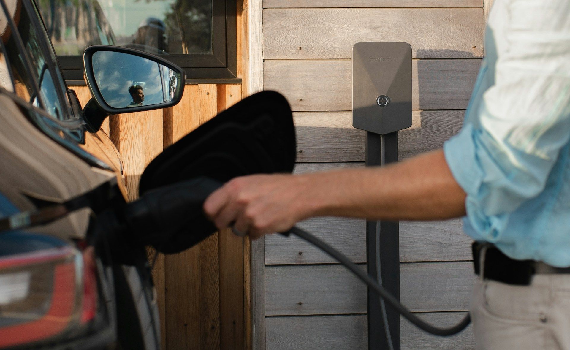 A person plugging an EV in to charge
